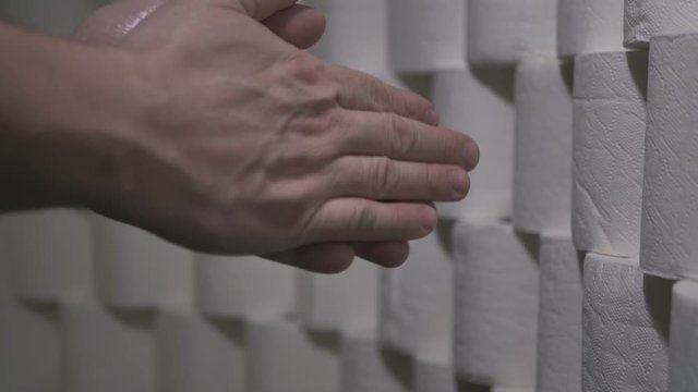 Male Carefully Disinfects Hands With Disinfectant Fluid. Background Wall Of Toilet Paper Rolls