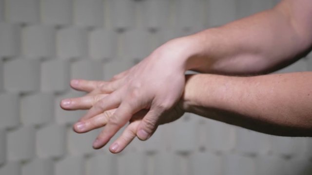 Man Carefully Rubs Disinfectant Into Hands. Background Wall Of Toilet Paper Rolls