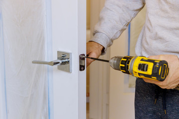 A man in installation a lock on a wooden door lock