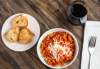 Overhead shot spaghetti with meat sauce, garlic bread and red wine