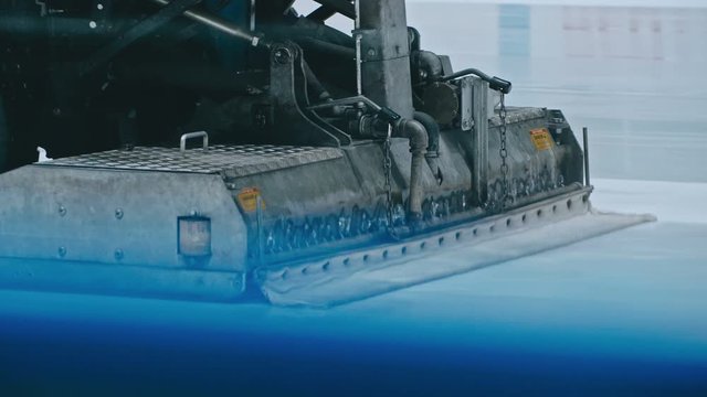 Zamboni resurfacing an indoor skating rink. Slow Motion. Ice resurfacer cleaning ice, machine cleaning and polishing smooth icerink. Ice harvester or restores ice.
