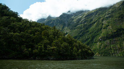 Rolling clouds come over mountains at the fjord Milford Sound in New Zealand