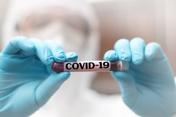 COVID-19 named by WHO for Novel coronavirus NCP concept. Doctor or lab technician in PPE suit holding blood sample with novel (new) coronavirus  in Wuhan, Hubei Province, China, medical and healthcare