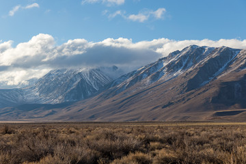 high desert landscape with snow capped mountains and clouds