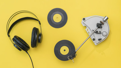Two yellow vinyl discs, headphones and a player on a yellow background.