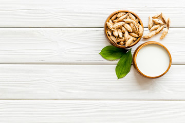 Alternative milk made from almond. Drink near unpeeled on white wooden table top-down copy space