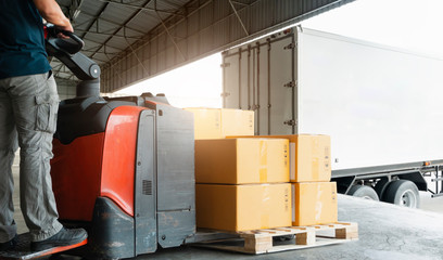 Workers Driving Forklift Pallet Jack Unloading Packaging Boxes on Pallet into Cargo Container...