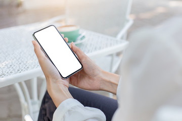 Mockup image blank white screen cell phone.woman hand holding texting using mobile on desk at coffee shop.background empty space for advertise text.people contact marketing business,technology