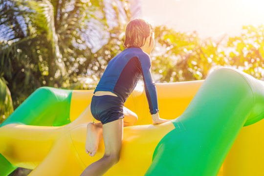 Cute boy runs an inflatable obstacle course in the pool