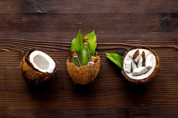 Coconut cosmetics. Organic oil in small bottles on dark wooden background top-down
