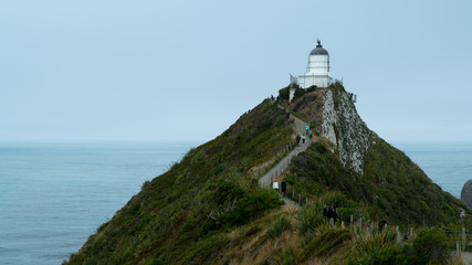 Nugget Point Lighthouse with hill and sea in New Zealand