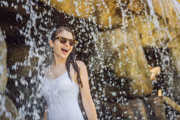 Obraz premium Young joyful woman under the water stream, pool, day spa, hot springs
