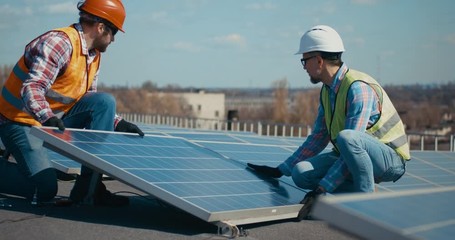 Technicians installing solar panels on metal stand