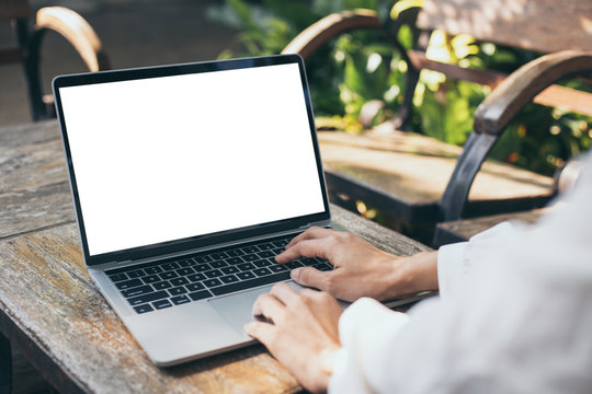 mockup image blank screen computer with white background for advertising text,hand woman using laptop contact business search information on desk at coffee shop.marketing and creative design