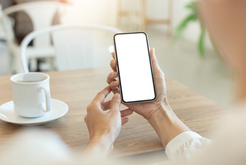 Mockup image blank white screen cell phone.woman hand holding texting using mobile on desk at coffee shop.background empty space for advertise text.people contact marketing business,technology