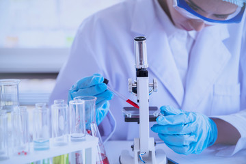Female scientist look at microscope, science test tube analyse scientific sample in laboratory...