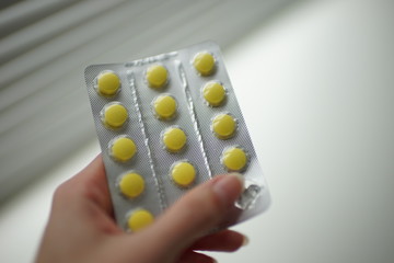 Blister with yellow vitamins in a female hand