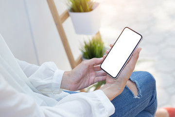 Mockup image blank white screen cell phone.woman hand holding texting using mobile sitting at coffee shop.background empty space for advertise text.people contact marketing business,technology