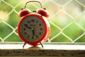 red alarm clock on wooden background