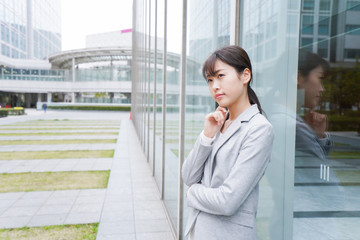 Fototapeta premium オフィス街で考えるビジネスウーマン
