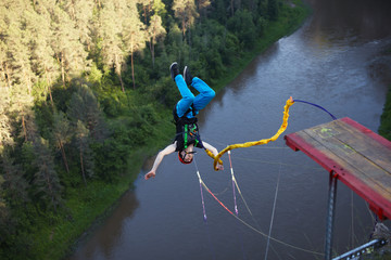 Extreme athlete, tied to a safety rope, makes a leap with a coup and falls upside down into a deep...