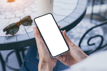 Mockup image blank white screen cell phone.woman hand holding texting using mobile on desk at coffee shop.background empty space for advertise text.people contact marketing business,technology