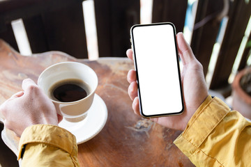 Mockup image blank white screen cell phone.man hand holding texting using mobile on desk at coffee shop.background empty space for advertise text.people contact marketing business,technology