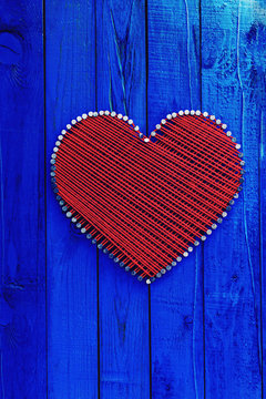 Antique Blue Wood Sign With Red And White Hearts On Burlap Background Hanging By Braided Rope On Aged Wooden Fence