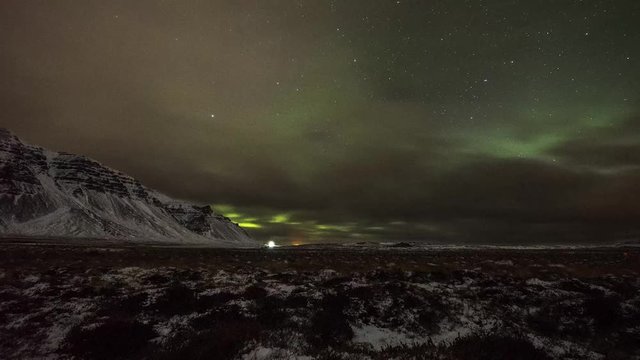 Timelapse of Northern Lights over Snowy Mountains in Iceland. Shot in Winter.