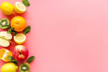 Oranges, lemon, apple, kiwi and grape - healthy food concept with fruits - on pink background top-down frame copy space