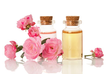 Obraz na płótnie Canvas Essential herbal rose oil for aromatherapy bottled for SPA and fresh flowers isolated on white background