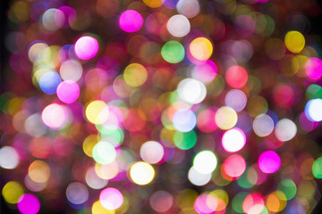 Fototapeta premium Pink, yellow and blue blurred festive bokeh. Christmas bright light holiday background.