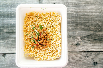 bowl of ramen soup. Tom Yam kun instant noodles with dried meat and vegetable additives on a wooden...