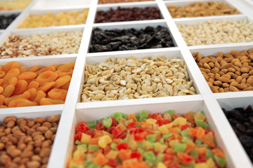 Peeled cashews lie in a square cell. In neighboring cells, nuts and other various grains are poured.