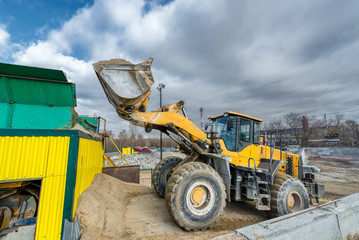 A wheel loader loads sand into a silo.