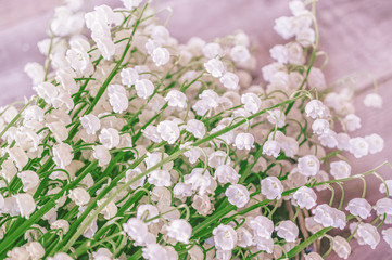 A large bouquet of lilies of the valley on a wooden table. Selective focus. Close up. Floral background