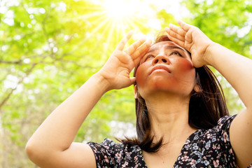 Asian woman having problem sunburn ,melasma, freckles on skin, hand cover her face to protect UV...