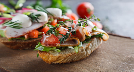 Bruschetta with tomatoes, bacon, herbs, mozzarella cheese , bell peppers, radishes and olives on an aged wooden Board. This is a classic Italian snack. Hot and crunchy bread