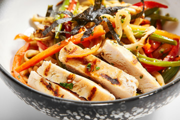 Wok udon with vegetables and chicken closeup view