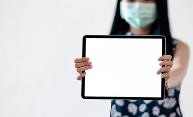 woman with protective mask showing blank screen tablet.
