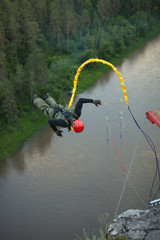 Athlete falls down against the background of a river tied to a safety rope. Ropejumping.
