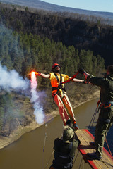 Man holding a smoke bomb in his hand jumps with a rope from a great height. Ropejumping.