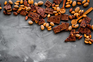 Sweets frame. Broken chocolate slices and nuts on grey stone background top-down copy space