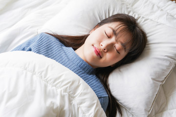 布団に入って睡眠を取る若い女性