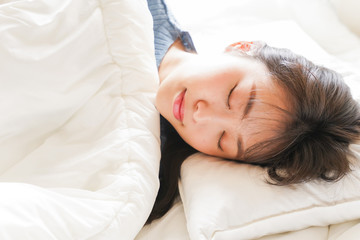 Obraz premium 布団に入って睡眠を取る若い女性