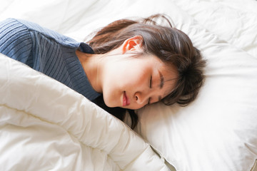 布団に入って睡眠を取る若い女性
