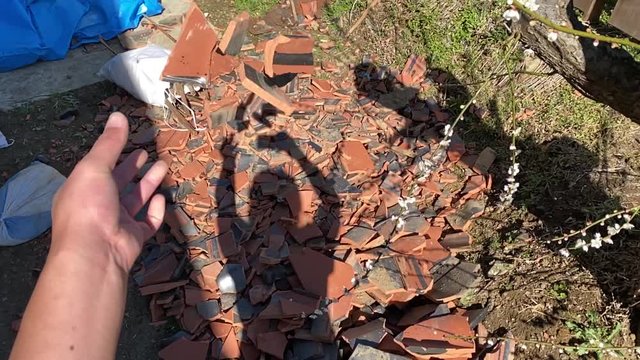 割れた瓦を投げる男性主観視点動画スローモーション。台風で割れた屋根瓦の撤去作業。地震/災害被害と修復/復旧作業/ボランティアイメージ
