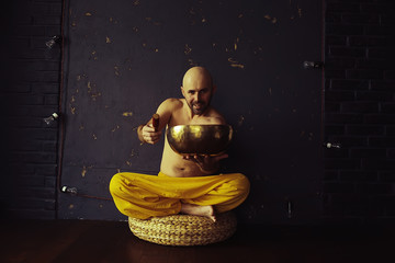 Tibetan singing bowl, a monk in yellow pants meditates and plays the musical bowl, Buddhism, religion