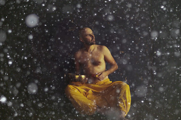 Tibetan singing bowl, a monk in yellow pants meditates and plays the musical bowl, Buddhism,...