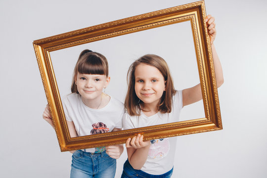 the concept of a healthy lifestyle , child protection, shopping - these are teenagers playing together. Happy children: sisters on a white background. Live picture - the girls look out of the frame